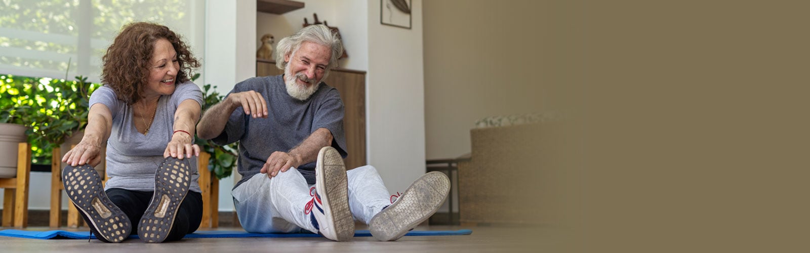 A man and woman stretching at home and laughing