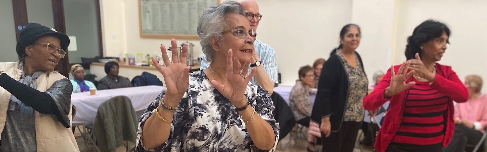 A group of older people with their hands held up, while dancing